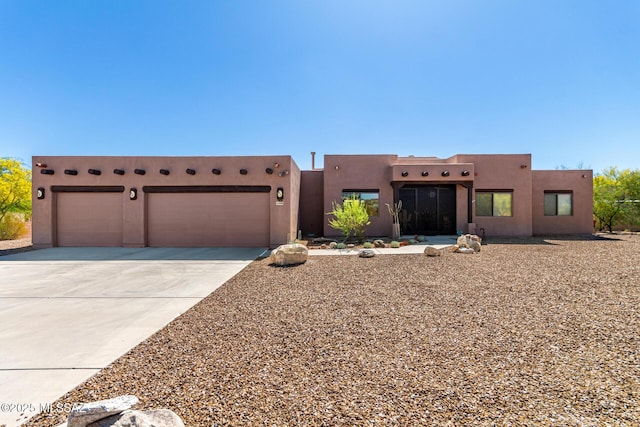 5498 N Desert Wood Pl, Tucson, AZ 85745 - pueblo-style house with a garage, stucco siding, and concrete driveway