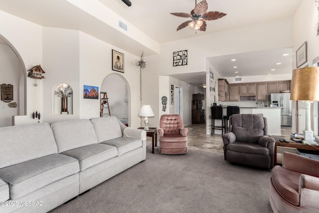 5498 N Desert Wood Pl, Tucson, AZ 85745 - living room with a high ceiling, light colored carpet, arched walkways, a ceiling fan, and visible vents