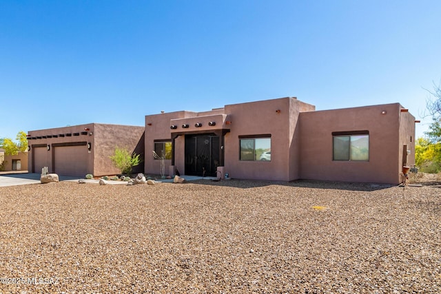 5498 N Desert Wood Pl, Tucson, AZ 85745 - pueblo-style house with an attached garage, driveway, and stucco siding