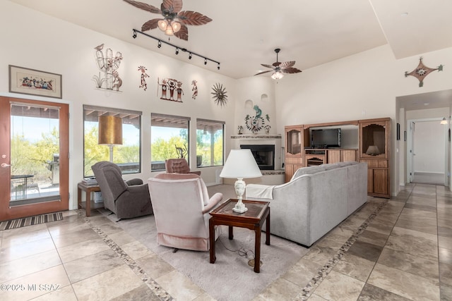 5498 N Desert Wood Pl, Tucson, AZ 85745 - living room featuring track lighting, a glass covered fireplace, a ceiling fan, light tile patterned floors, and a towering ceiling