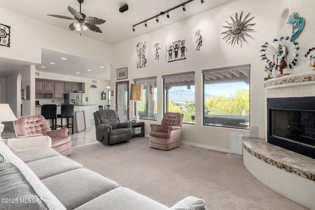 5498 N Desert Wood Pl, Tucson, AZ 85745 - living room featuring track lighting, baseboards, ceiling fan, light colored carpet, and a fireplace with raised hearth