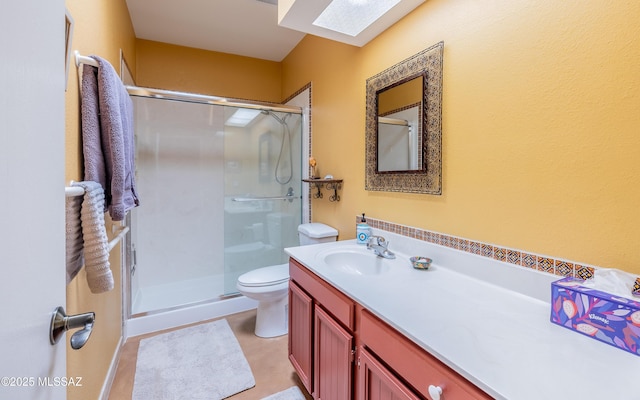 full bathroom with vanity, a stall shower, a skylight, and toilet