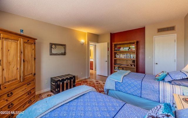 bedroom featuring baseboards, a textured ceiling, and visible vents