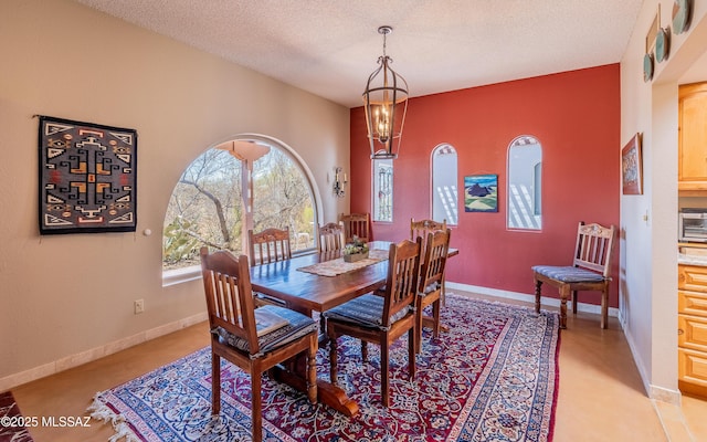dining room featuring baseboards, a textured ceiling, and a chandelier