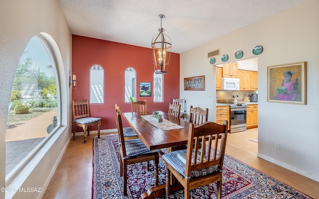 dining space featuring a textured ceiling, visible vents, and a wealth of natural light