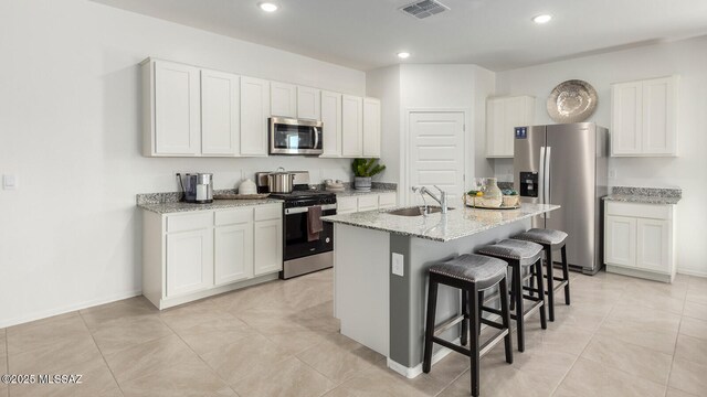 9828 E Gray Hawk Dr, Tucson, AZ 85730 - kitchen with a breakfast bar area, appliances with stainless steel finishes, white cabinets, a sink, and visible vents
