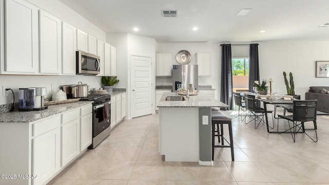 9828 E Gray Hawk Dr, Tucson, AZ 85730 - kitchen with a sink, a kitchen bar, visible vents, white cabinetry, and appliances with stainless steel finishes