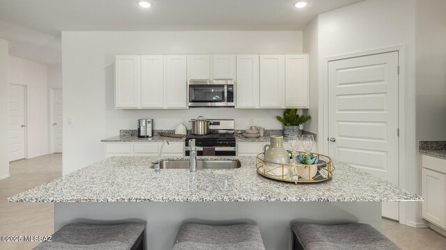 9828 E Gray Hawk Dr, Tucson, AZ 85730 - kitchen with a breakfast bar, a sink, appliances with stainless steel finishes, and white cabinetry