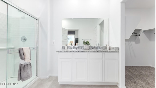 9828 E Gray Hawk Dr, Tucson, AZ 85730 - bathroom featuring a sink, double vanity, a stall shower, baseboards, and a spacious closet
