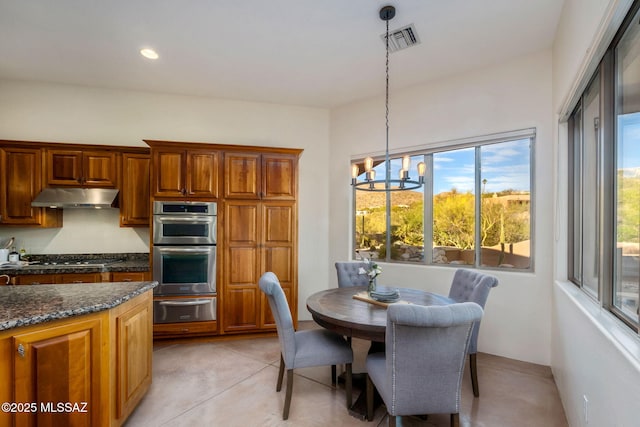 6340 N Placita Alta Reposa, Tucson, AZ 85750 - interior space featuring under cabinet range hood, a warming drawer, visible vents, pendant lighting, and a notable chandelier
