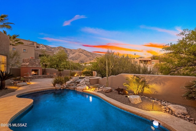6340 N Placita Alta Reposa, Tucson, AZ 85750 - pool at dusk featuring a patio, a warm lit fireplace, a fenced in pool, a mountain view, and fence