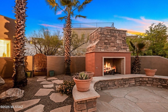 6340 N Placita Alta Reposa, Tucson, AZ 85750 - patio terrace at dusk featuring a gate and an outdoor stone fireplace