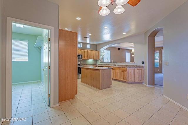 kitchen featuring appliances with stainless steel finishes, light tile patterned floors, recessed lighting, and arched walkways