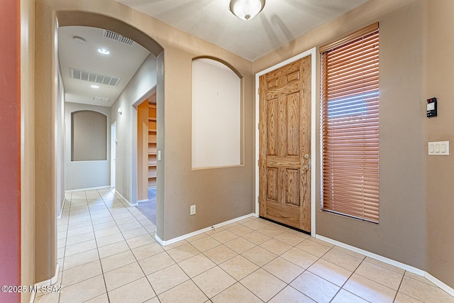 foyer with light tile patterned flooring, visible vents, baseboards, and arched walkways