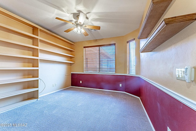 carpeted spare room featuring a ceiling fan and baseboards