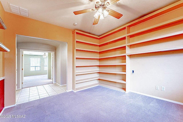 carpeted spare room with ceiling fan, baseboards, tile patterned floors, and visible vents