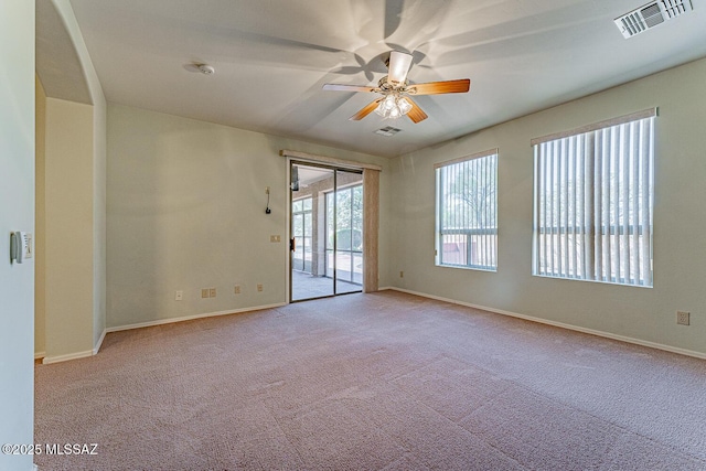 carpeted empty room with visible vents, ceiling fan, and baseboards