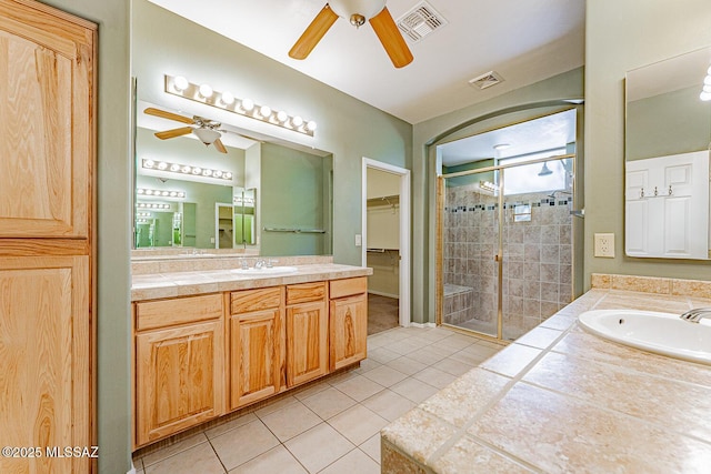 full bathroom featuring ceiling fan, a shower stall, visible vents, and tile patterned flooring
