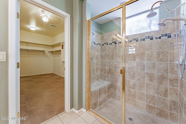 bathroom with a stall shower, a walk in closet, visible vents, baseboards, and tile patterned flooring