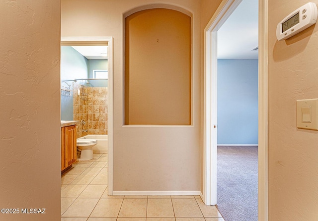 hallway featuring baseboards, light tile patterned floors, and arched walkways