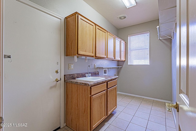 laundry room featuring washer hookup, light tile patterned floors, a sink, baseboards, and cabinet space