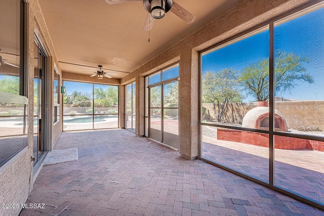 unfurnished sunroom featuring ceiling fan