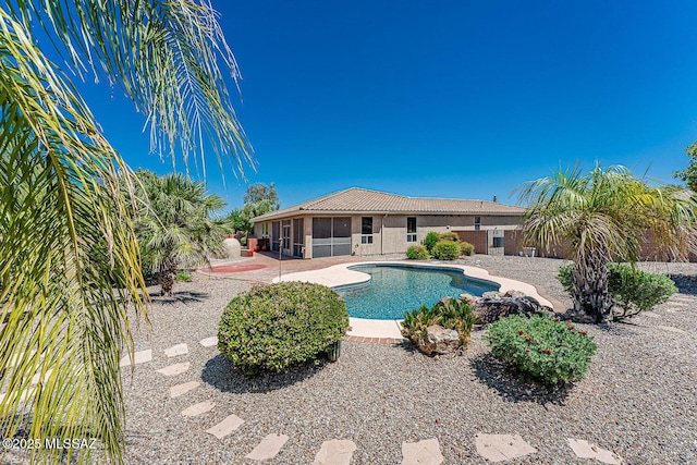 pool featuring a sunroom, a patio, and a fenced backyard