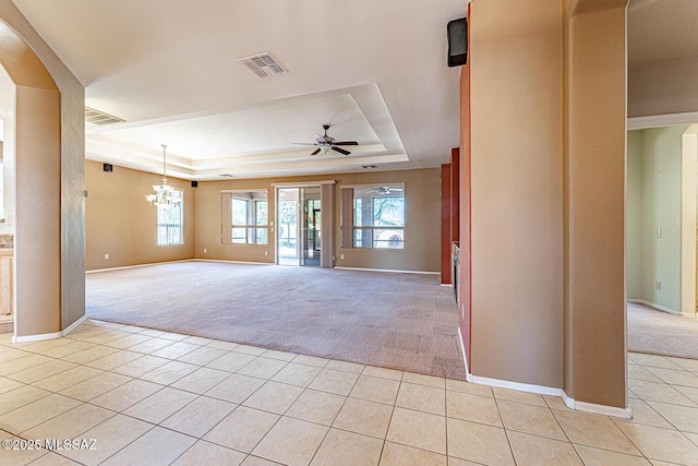 empty room with visible vents, light tile patterned floors, light colored carpet, and a tray ceiling
