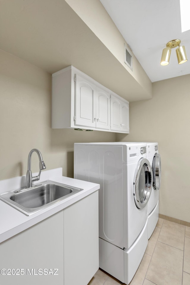 washroom featuring visible vents, cabinet space, a sink, light tile patterned floors, and washer and clothes dryer