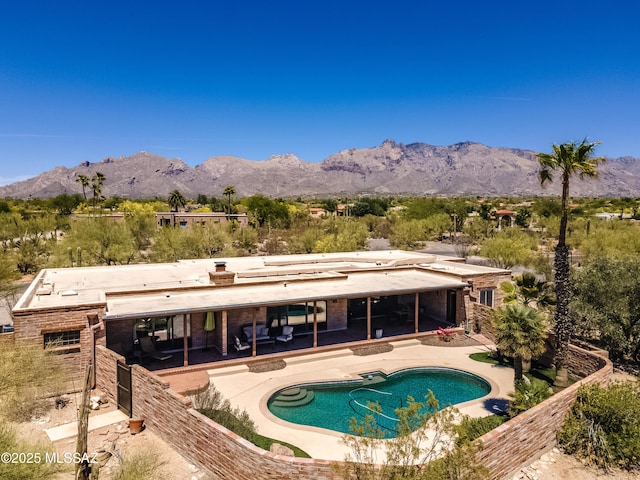 pool with fence, a mountain view, and a patio area
