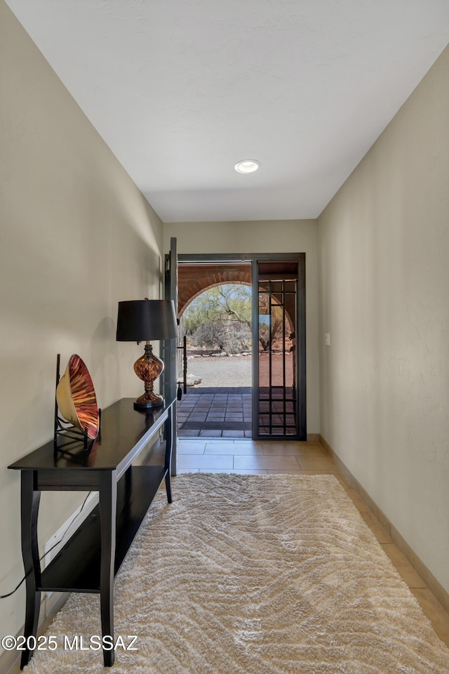 doorway with tile patterned floors and baseboards