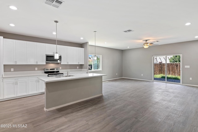 3000 S Smokin Pistol Way, Tucson, AZ 85713 - kitchen featuring stainless steel appliances, light countertops, a kitchen island with sink, ceiling fan, and baseboards