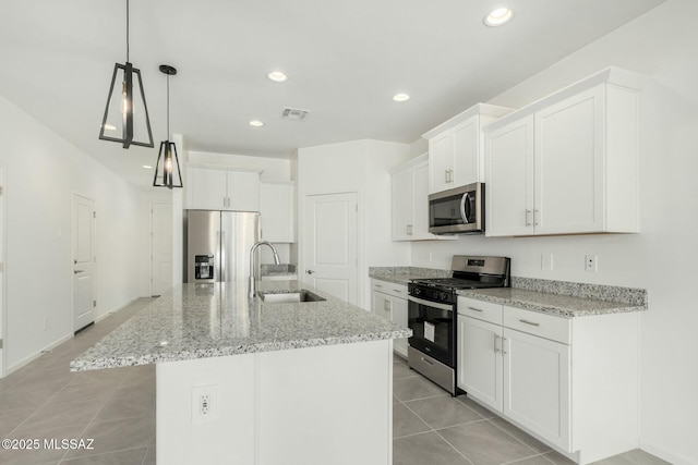 kitchen with appliances with stainless steel finishes, white cabinets, a sink, visible vents, and light tile patterned flooring