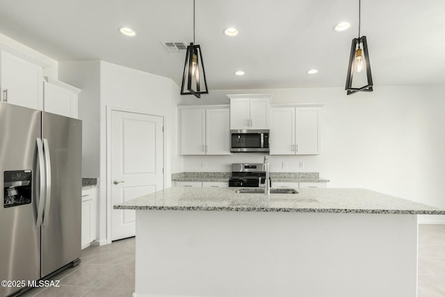 kitchen with light stone counters, appliances with stainless steel finishes, white cabinets, a sink, and a center island with sink