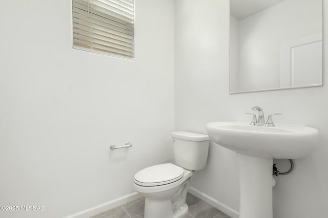 half bathroom with tile patterned floors, toilet, and baseboards