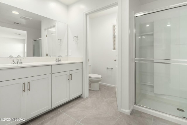 bathroom with a shower stall, a sink, double vanity, toilet, and tile patterned flooring