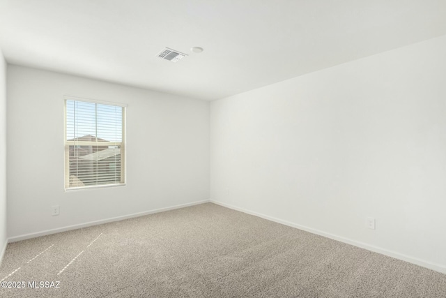 empty room featuring baseboards, visible vents, and light carpet