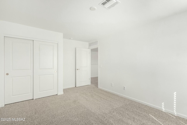 unfurnished bedroom with a closet, visible vents, carpet floors, and baseboards