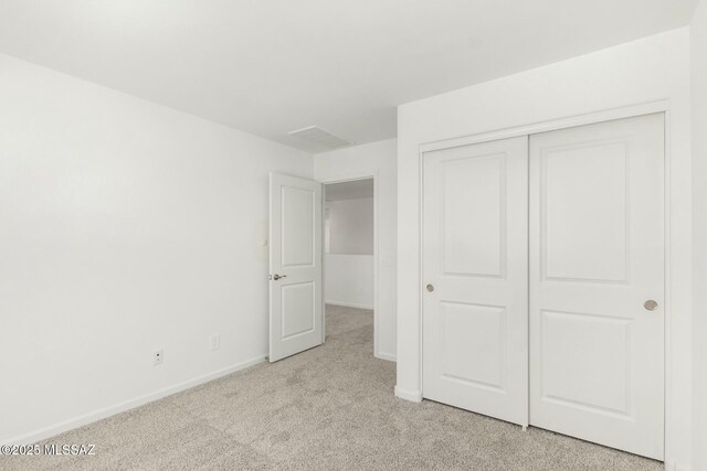 unfurnished bedroom featuring light colored carpet, a closet, and baseboards