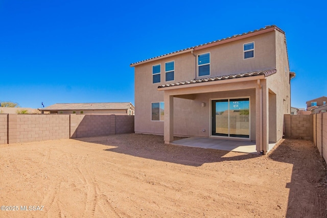 rear view of house featuring a fenced backyard, stucco siding, a tiled roof, and a patio area