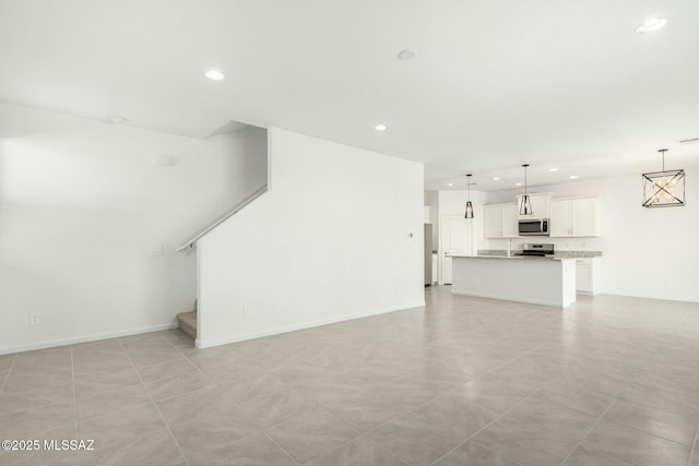 unfurnished living room featuring recessed lighting, baseboards, and stairs