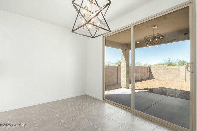 unfurnished dining area featuring tile patterned flooring, an inviting chandelier, and baseboards