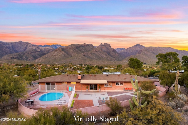 pool at dusk featuring a fenced backyard, a patio, and a mountain view
