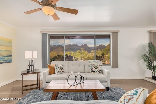 living room with wood finished floors, baseboards, ceiling fan, crown molding, and a mountain view
