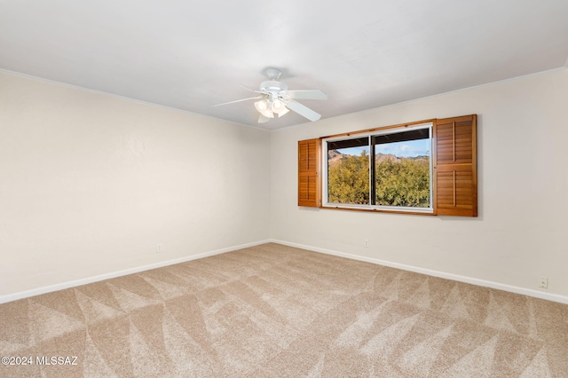 carpeted spare room with a ceiling fan and baseboards