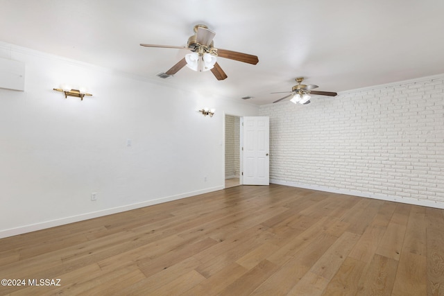 empty room with brick wall, crown molding, a ceiling fan, baseboards, and wood finished floors