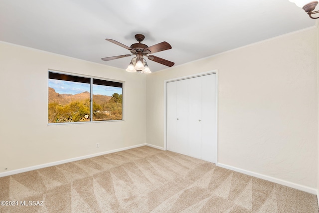 unfurnished bedroom featuring carpet flooring, a closet, baseboards, and ceiling fan