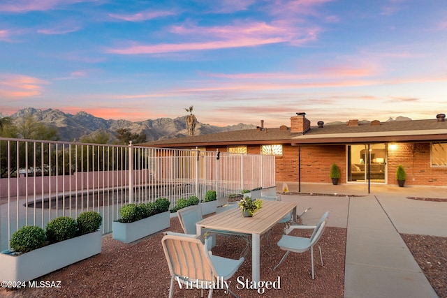 patio terrace at dusk with a mountain view and fence