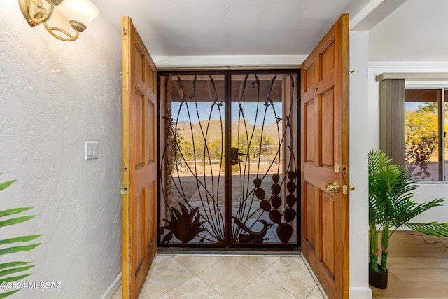 doorway to outside with baseboards and light tile patterned flooring