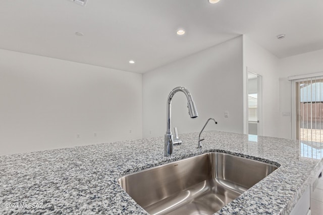 interior details featuring light stone counters, recessed lighting, and a sink